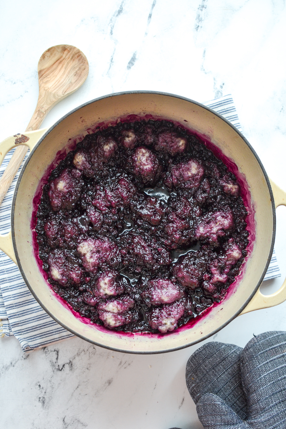 A Dutch Oven filled with blueberries and dumplings.