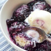 A bowl of blueberry grunt topped with a scoop of ice cream.