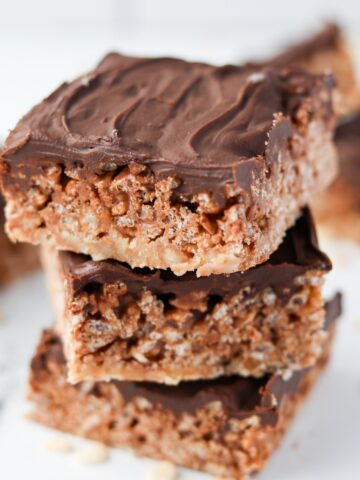 A stack of three Mars Bar squares on top of each other, topped with chocolate.