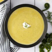 A bowl of soup garnished with sour cream and dill.
