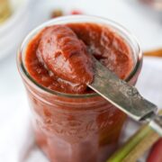 A knife taking a portion of rhubarb butter from a jar.