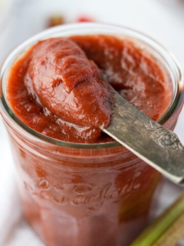 A knife taking a portion of rhubarb butter from a jar.