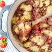 A Dutch Oven filled with a fruit grunt topped with biscuits.