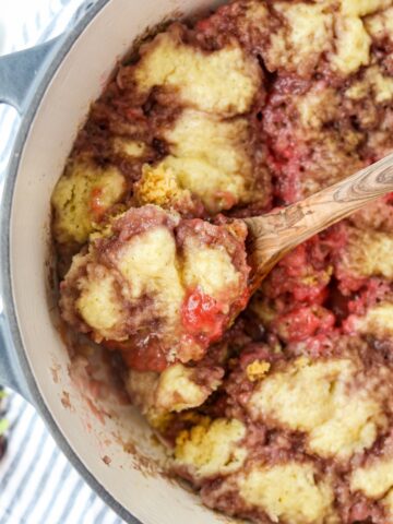 A Dutch Oven filled with a fruit grunt topped with biscuits.