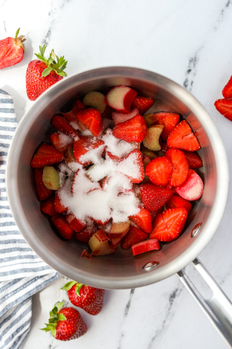 A saucepan filled with fruit and sprinkled with sugar.