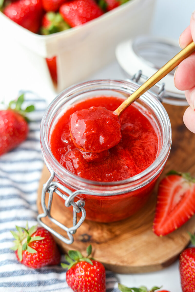 Taking a spoonful of strawberry rhubarb compote from a jar.