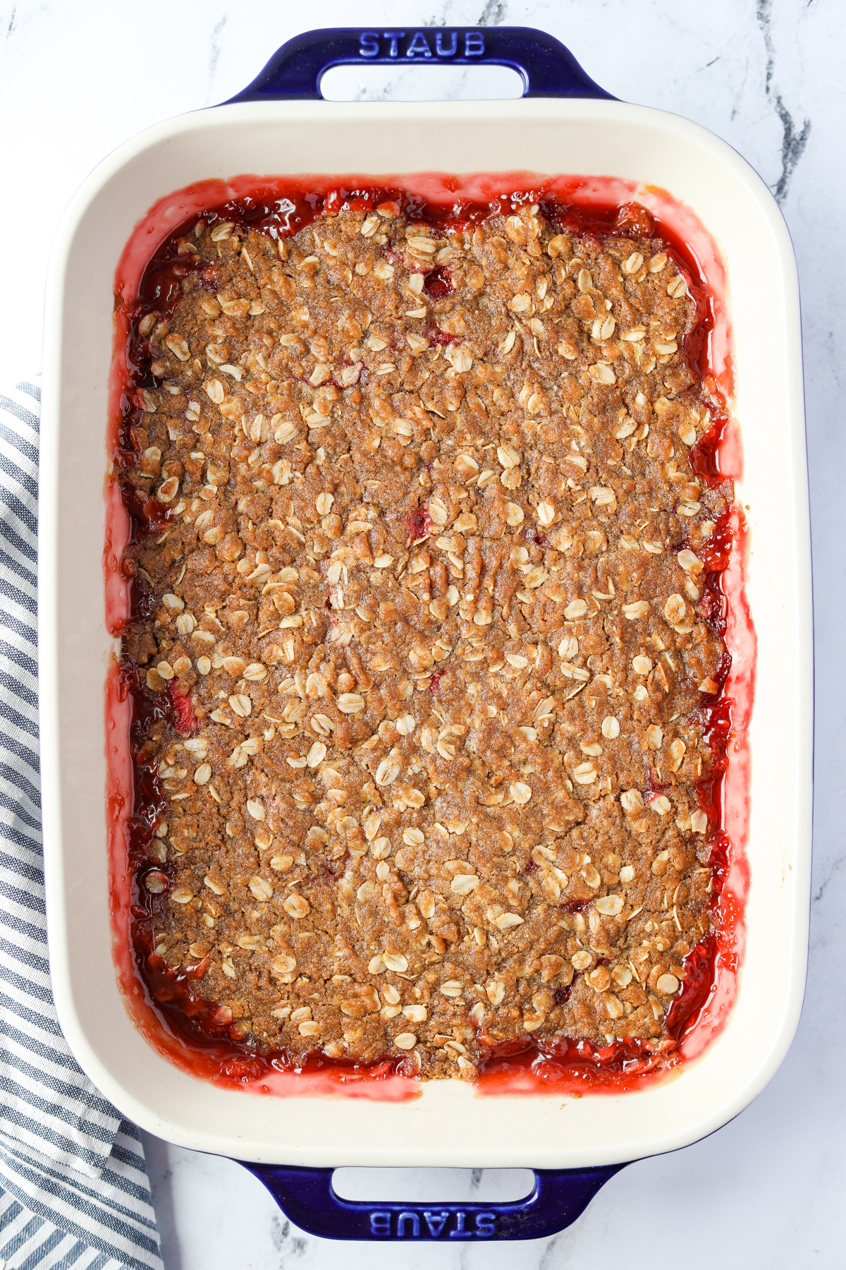 A baking dish with a strawberry and rhubarb fruit crisp baked inside.