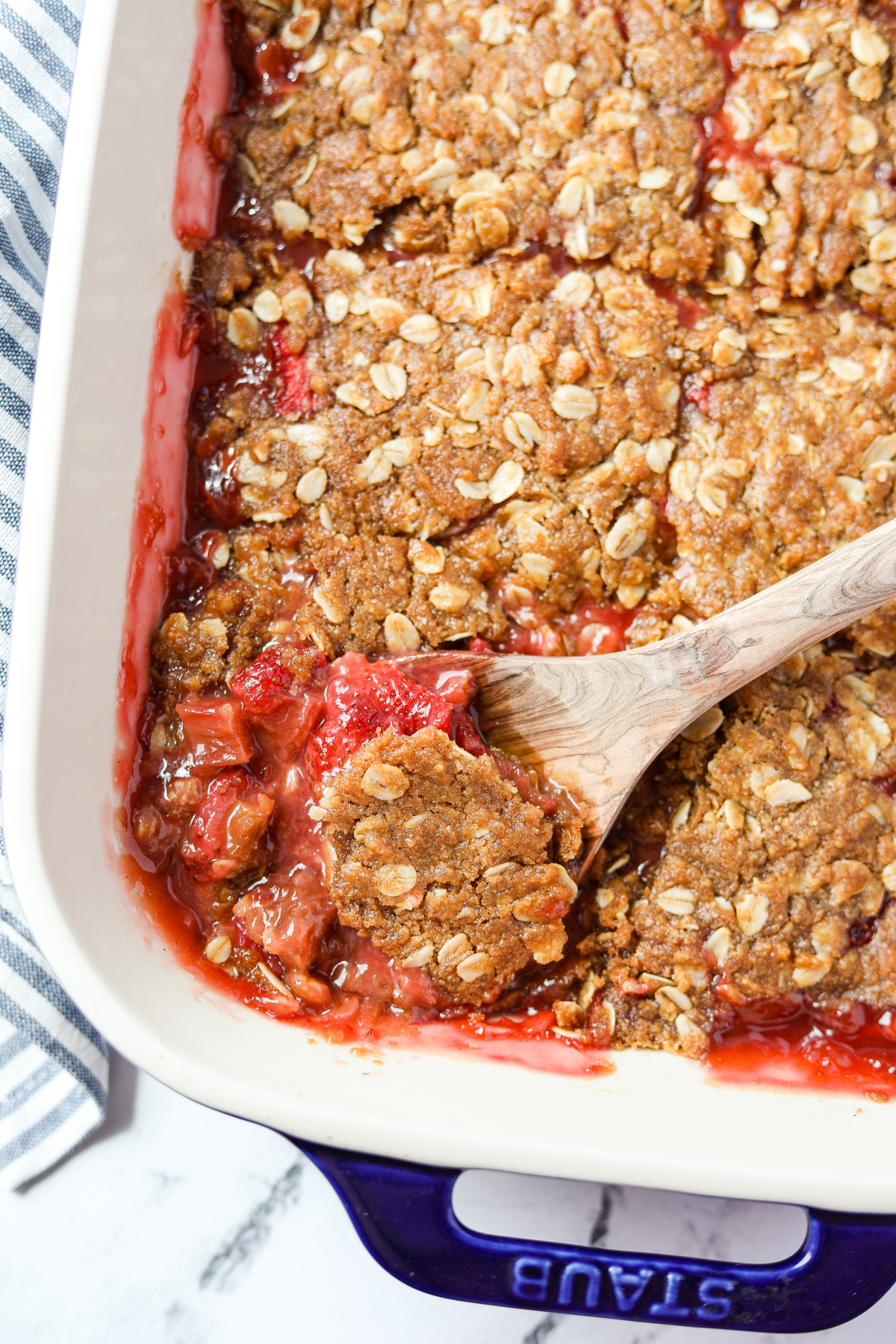 A baking dish filled with a fruit crisp made with rhubarb and strawberries.