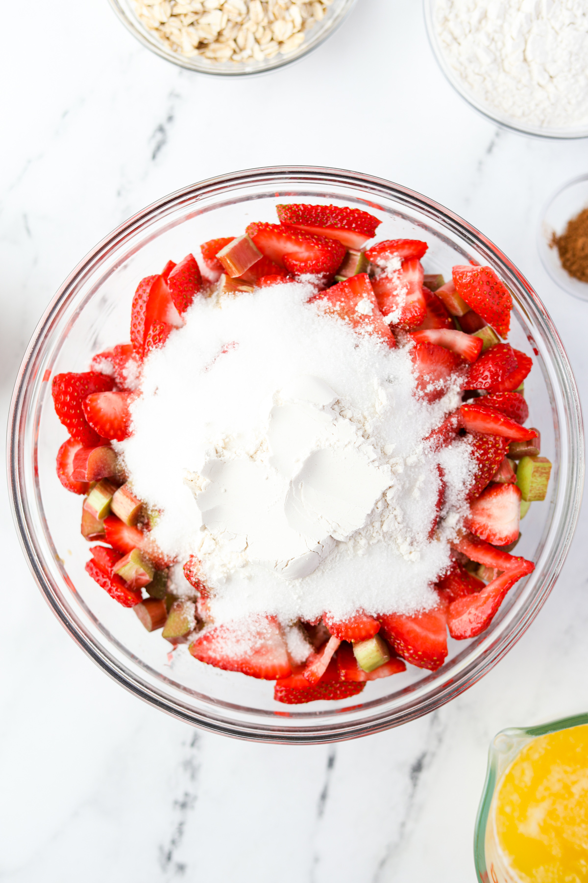 A bowl of strawberries and rhubarb with sugar.
