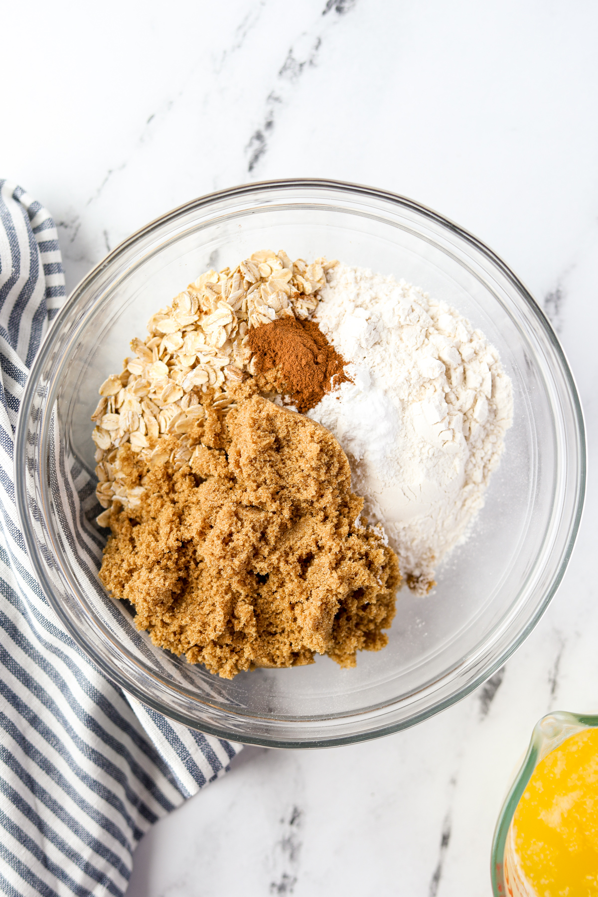 A bowl of dry ingredients: flour, oats, brown sugar, and cinnamon.