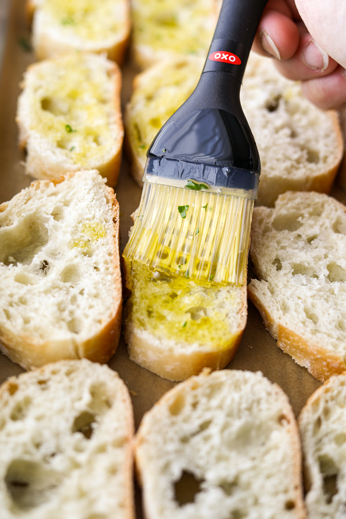 Brushing olive oil on slices of bread.