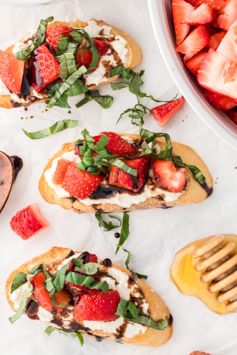 Baguette slices topped with ricotta, strawberries, basil, and balsamic glaze.