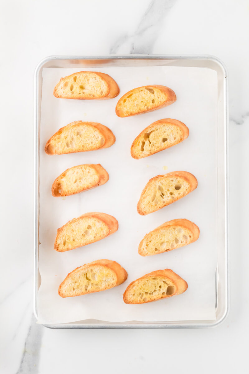 Toasted baguette slices on a baking sheet.