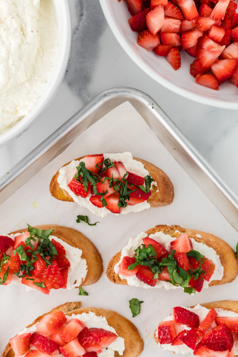 Crostini topped with ricotta, fresh strawberries, and basil.