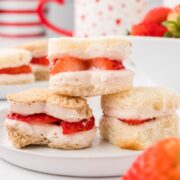 A stack of three strawberry sandwiches filled with fresh fruit and cream cheese.