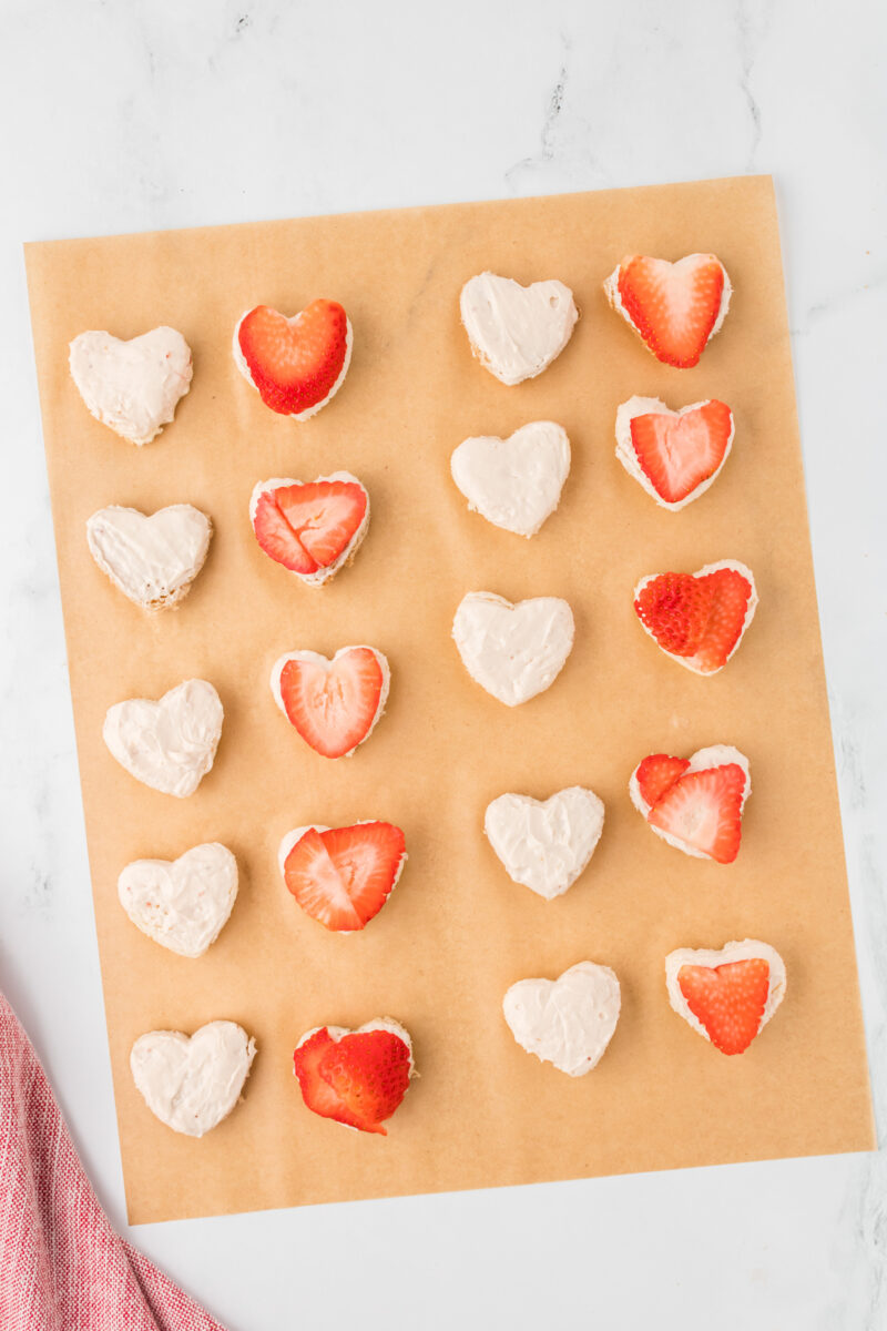 Heart-shaped sandwich halves, with sliced strawberries on one half.