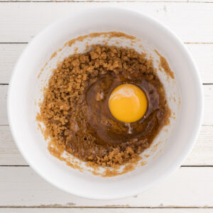 A bowl of brown sugar and oil mixed together with egg.