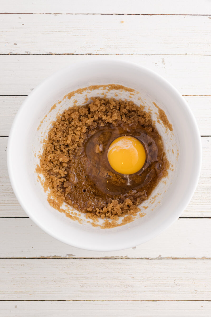 A bowl of brown sugar and oil mixed together with egg.