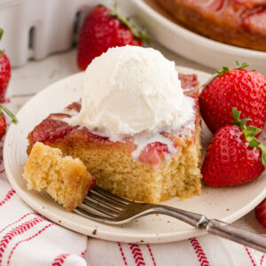 A slice of strawberry upside down cake with a scoop of vanilla ice cream on top.