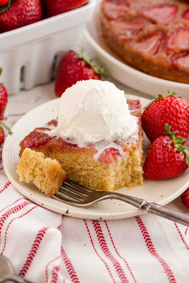 A slice of strawberry upside down cake with a scoop of vanilla ice cream on top.