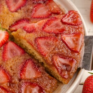 A cake lifter taking a slice of strawberry cake from a serving platter.