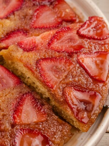 A cake lifter taking a slice of strawberry cake from a serving platter.